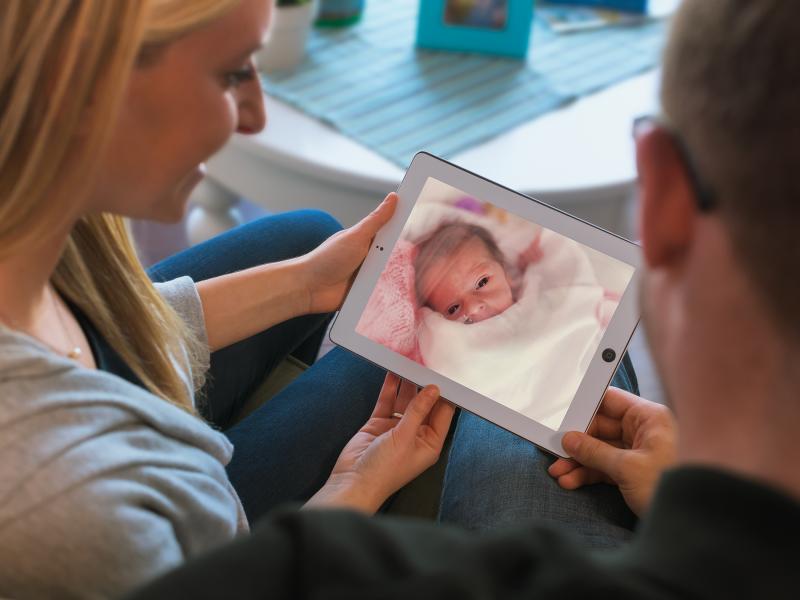Couple looking at baby on a tablet screen 