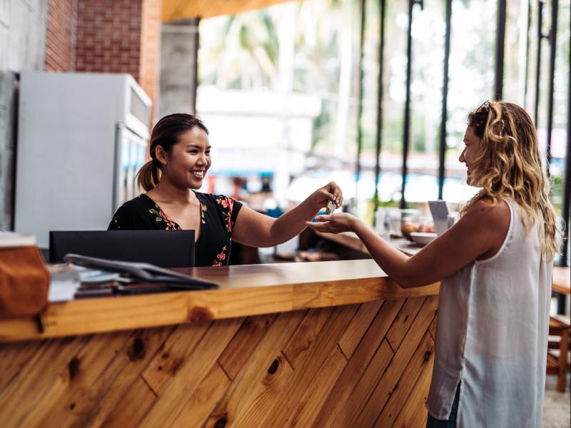 Hotel clerk handing over key to women in reception