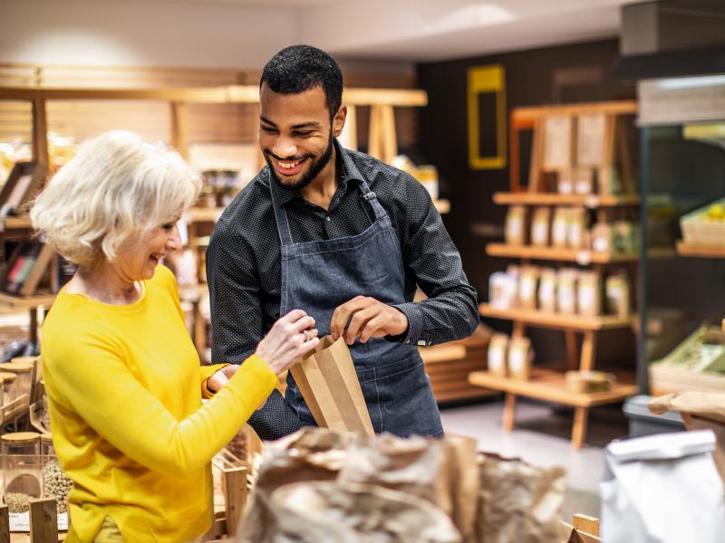 Man helping woman in a bulk foods store