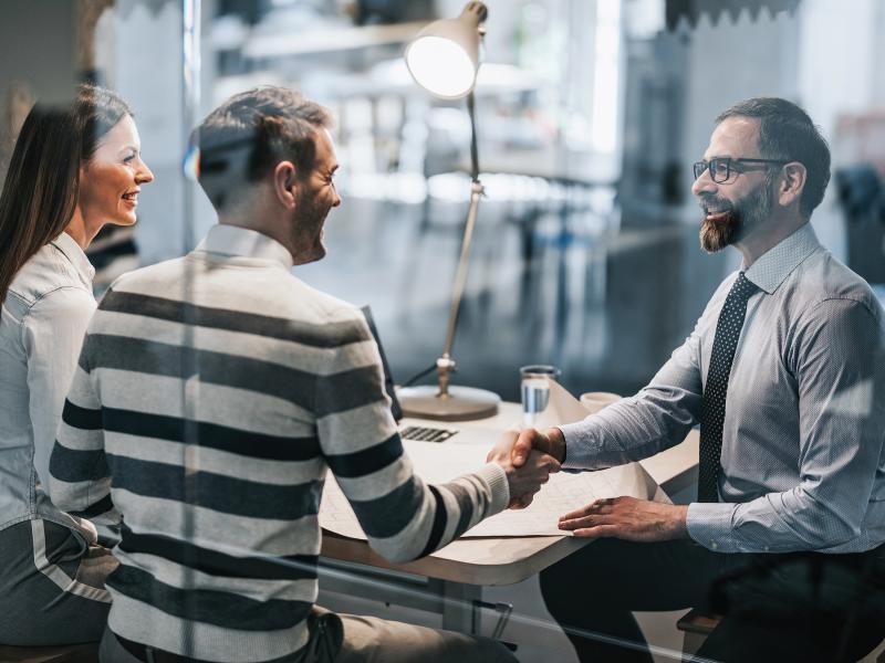 Three people in a meeting two person shake hands