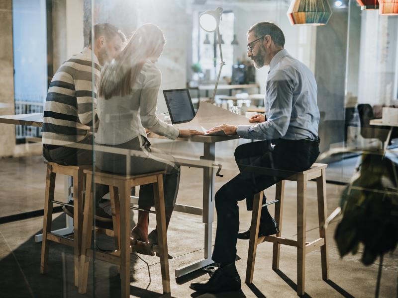 Three people in a meeting looking at documents on a table