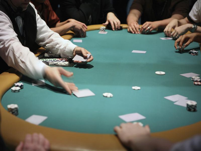 Card dealer hands out cards to poker players 