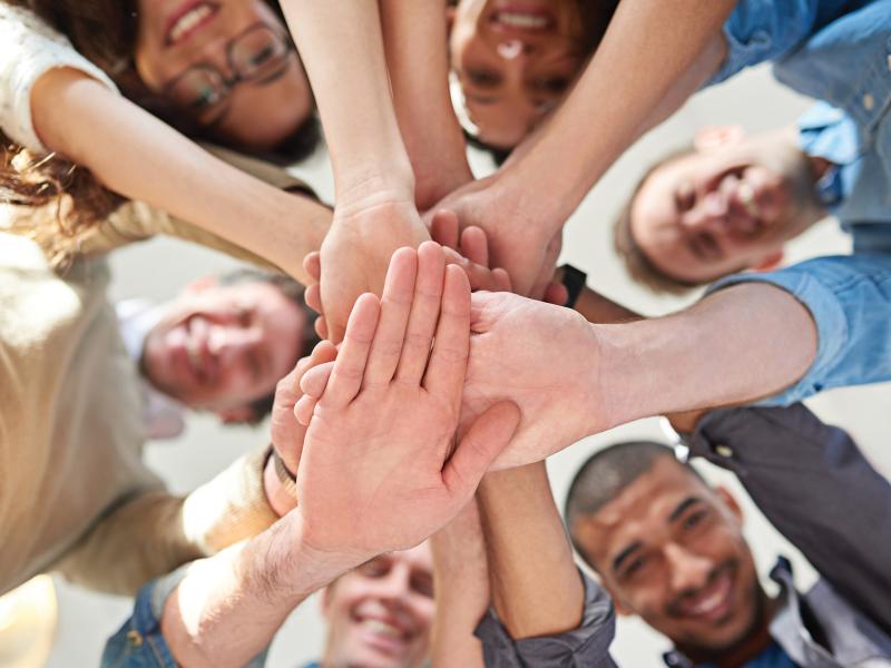 Big group of people smiling while handstacking above the camera.