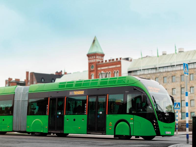 Green bus driving in a city