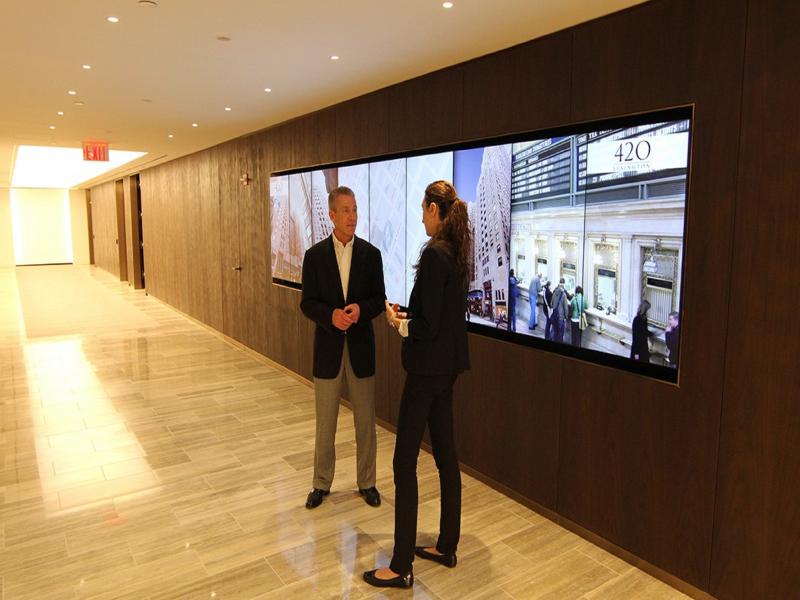 Two people in hallway with monitors behind them