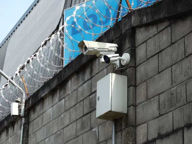 Cameras on brick wall with barbed wire