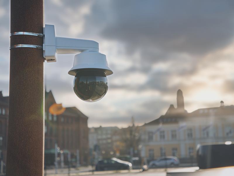 Axis camera mounted on pole in city with sky in background.