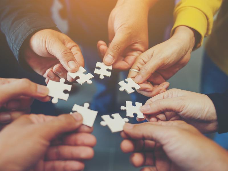 circle of hands, holding puzzle pieces