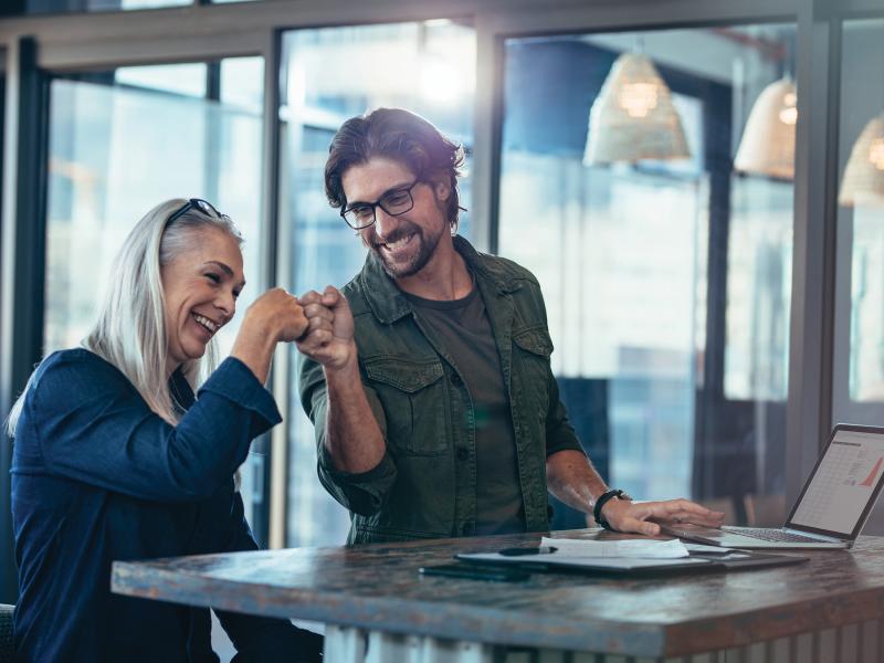 Woman and man smiling while doing a fist bumb