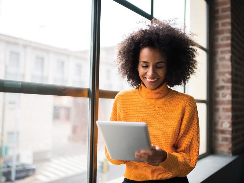 Woman with orange sweater holding a tablet