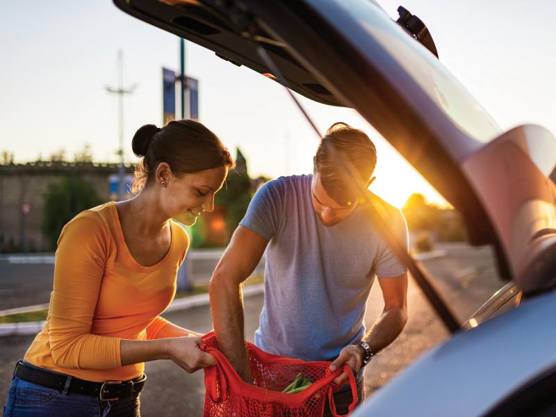 couple putting groceries in a car trunk at sunset