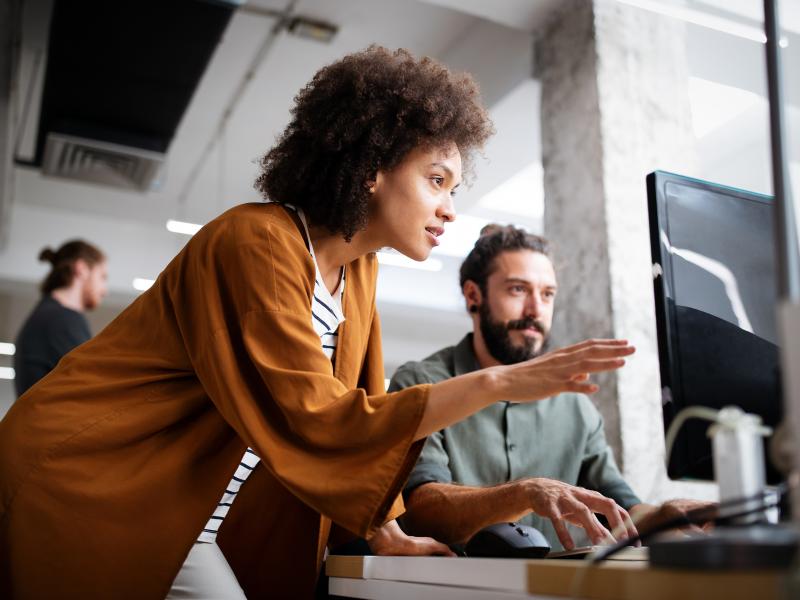 Woman explaining for a man in front of a computer