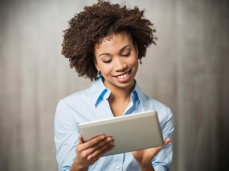 Business woman, holding a tablet. Grey background. 