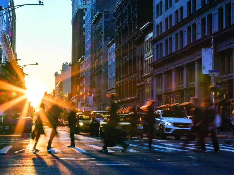 Crosswalk in the big city with people crossing and cars waiting