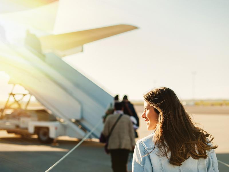 Woman passenger boarding plane in sunset