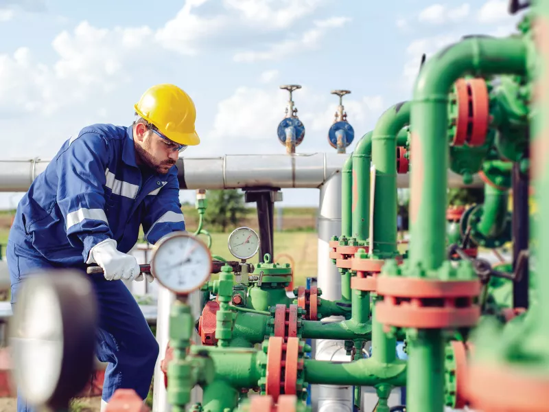 Man in hardhat adjusting oil pipes