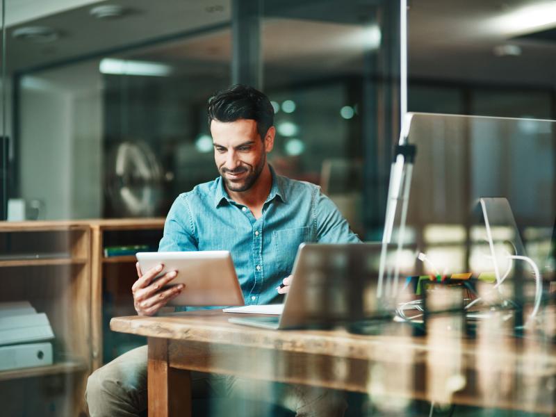 Man sitting by a desk with a tablet in his hands