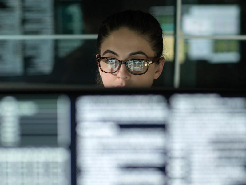 Woman with glasses sitting by the computer looking over the screen