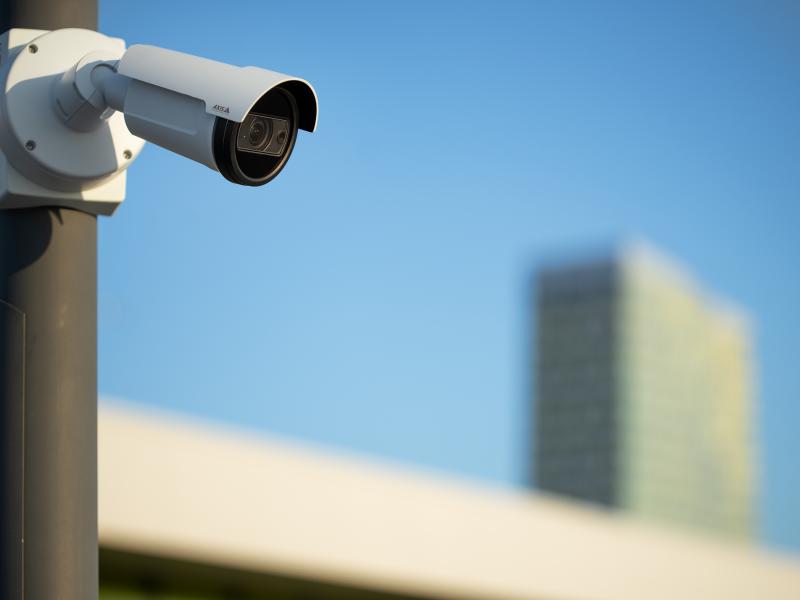 P1467-LE mounted on a pole in a city. High-rise building in the background.