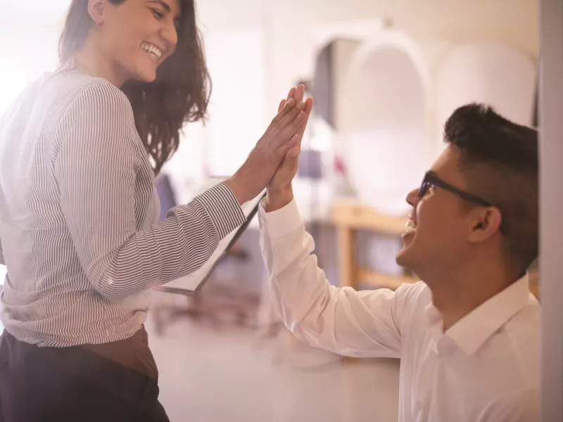 woman and man in an office environment, high five