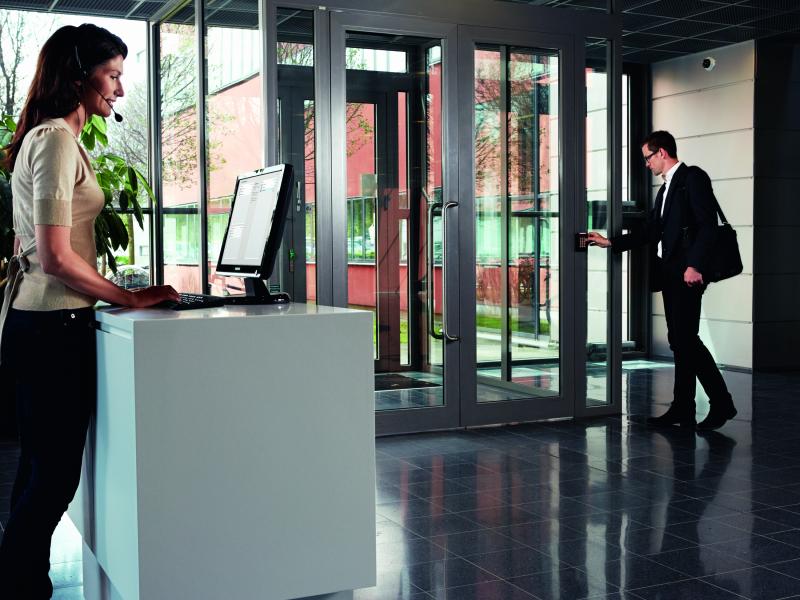 Man using access control to get through door and woman working by desk