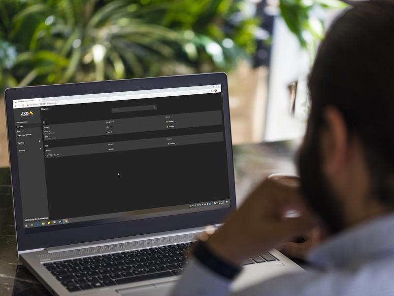 man, sitting in front of a laptop screen. green plants in the background