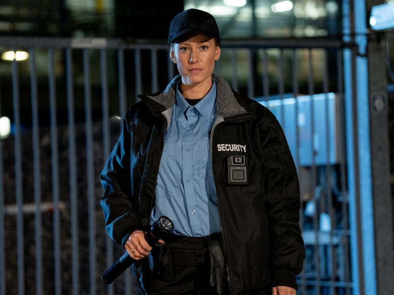 night time, security guard holding a flashlight, standing in front of a fence, outdoors