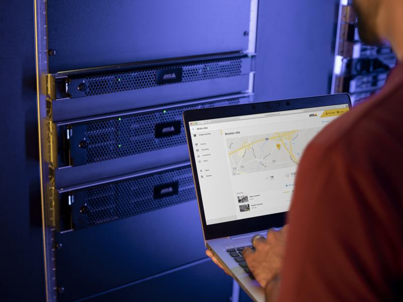 server technician in a serverroom, looking at a laptop screen