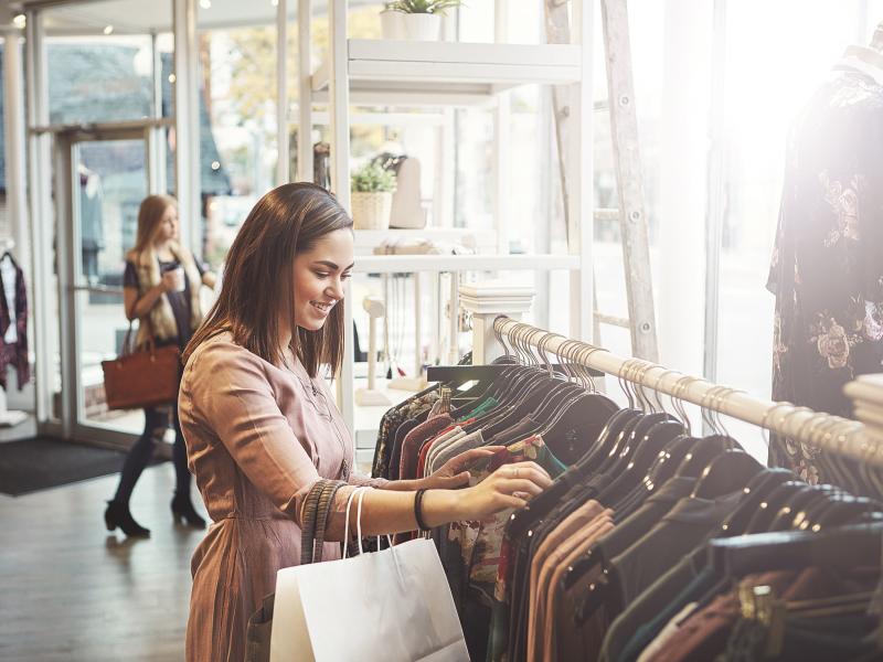 Person standing next to a clothing rack going through the clothes hanging