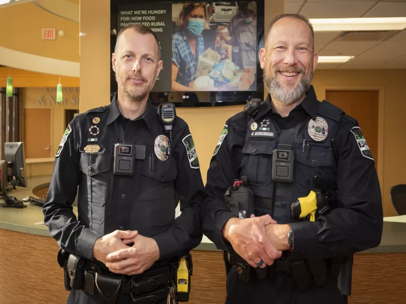 2 campus police officers pose with Axis body worn cameras on vests