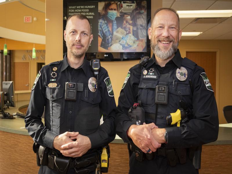 2 campus police officers pose with Axis body worn cameras on vests
