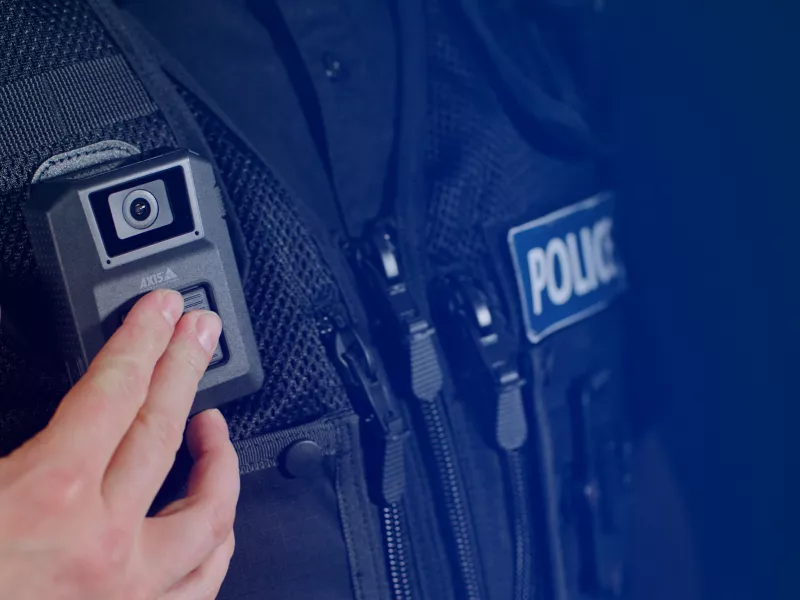 Police officer in black vest pushing button.