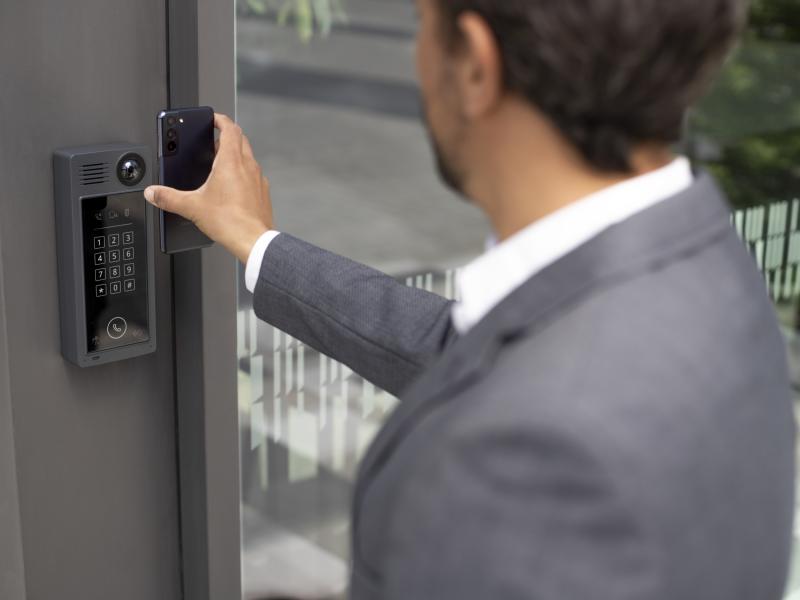 man using phone at a door controller