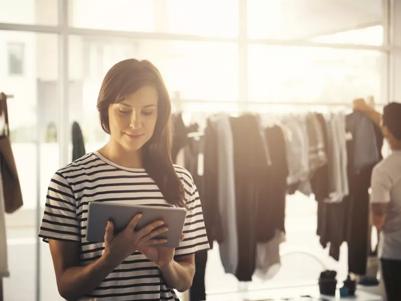 woman in a clothing store, holding a tablet
