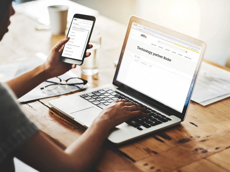 business woman infront of laptop, holding a smartphone in her hand