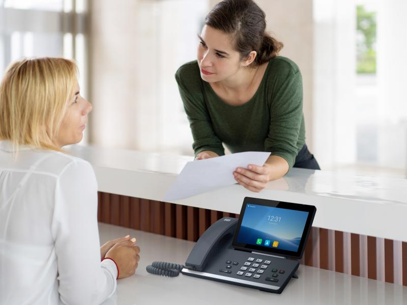 receptionist in an office environment, talking to a colleague