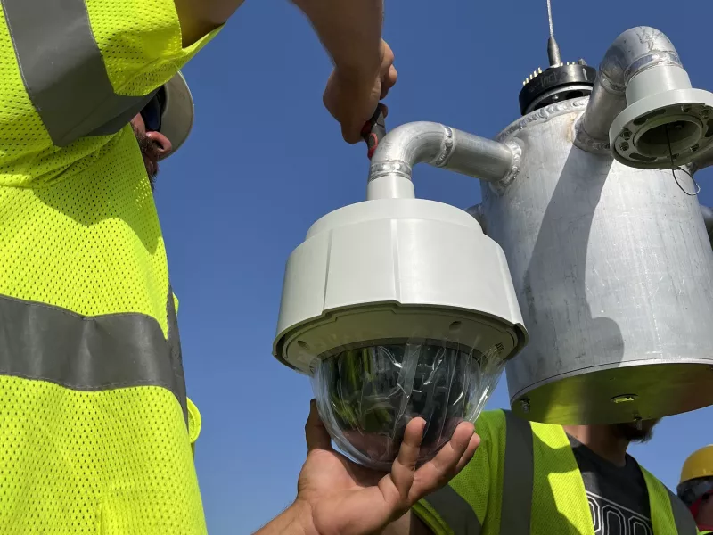 Worker screwing camera on lowering mount