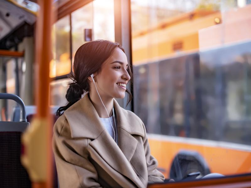 woman seated in a bus with earphones