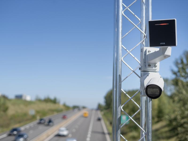 AXIS D2210-VE Radar and AXIS P1465-LE Bullet Camera mounted near a highway. Traffic visible in the background.