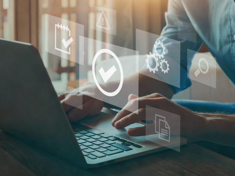 hands on laptop virtual icons checkmark and cogwheels overlay