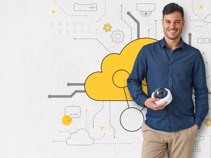 man standing holding a camera, behind a wall with yellow cloud illustration