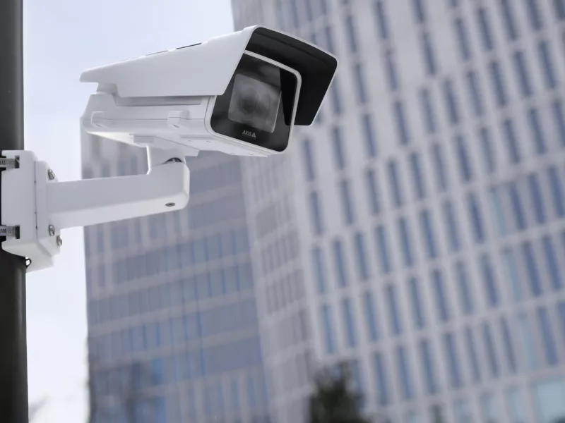 Box camera mounted on pole outside with office building in the background