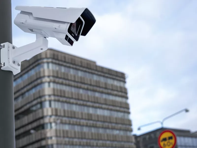 Camera mounted on pole outside with office building in the background