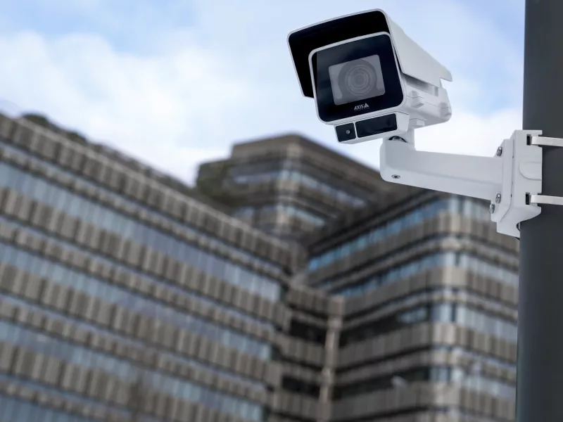 Camera mounted on pole outdoor with office building in the backgroudn