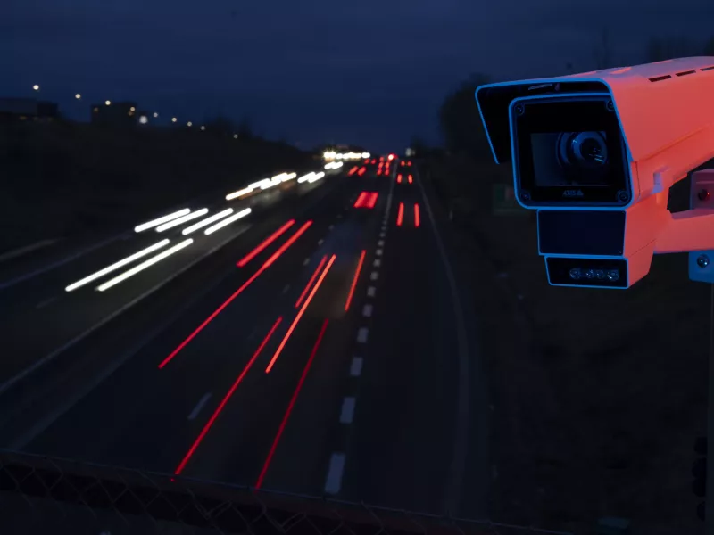 Dark night with camera to the right and highway with cars in the background