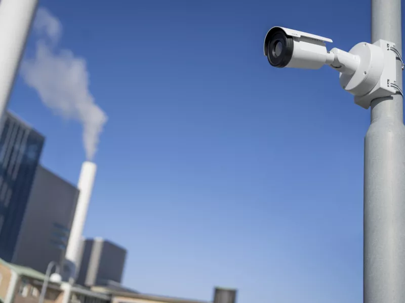 Thermal camera installed on a pole looking towards chimney with smoke.