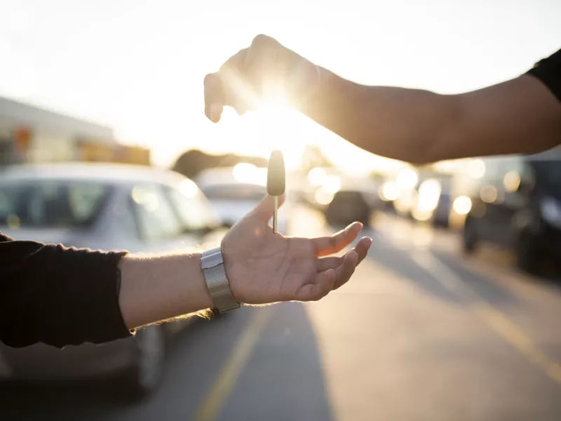 Handing over car key in sunlight