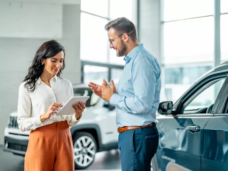 Woman with ipad and man by car