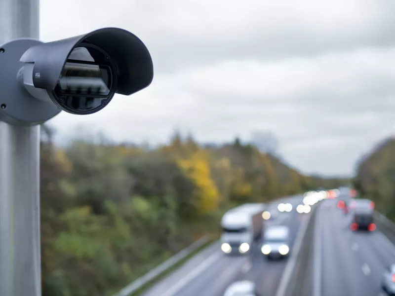 Camera mounted on a pole overlooking highway with cars