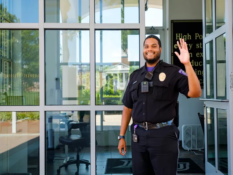 Security officer with body worn camera waving to camera